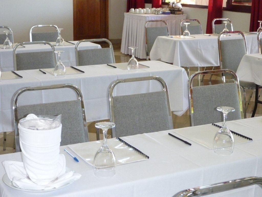Une salle de conférence avec des tables disposées pour les réunions, équipée de blocs-notes, de stylos et de verres.