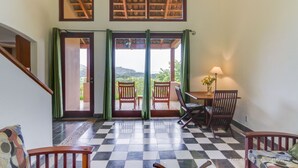 Una habitación con suelo a cuadros, una escalera, vista a través de una puerta y una mesa con sillas.