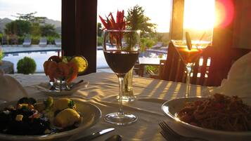 A table set for dinner with plates of food, a glass of red wine, and a martini glass.