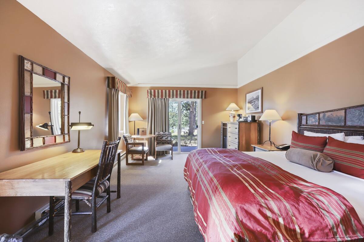 Une chambre d’hôtel équipée d’un lit, d’un bureau, d’une chaise et offrant une vue sur l’extérieur.