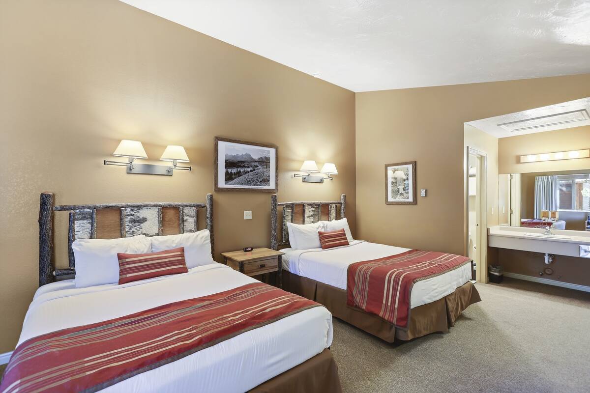 Une chambre d’hôtel avec deux lits, une salle de bain et un tableau au mur.