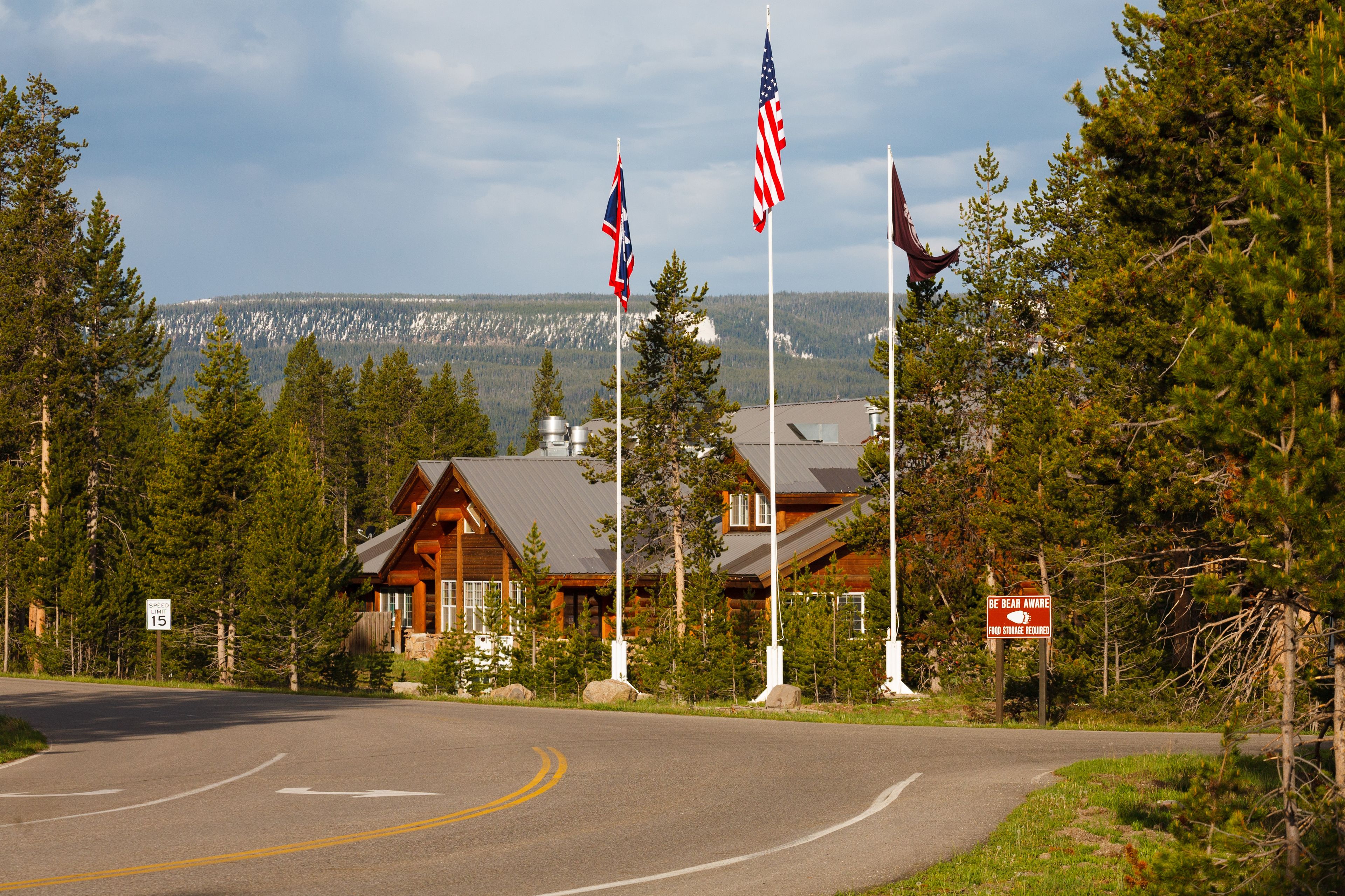 A lodge with a curved road, multiple flags, and a warning sign.