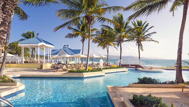 A pool area with lounge chairs, palm trees, and a gazebo overlooking the ocean. - Magdalena Grand Beach & Golf Resort (Lowlands)