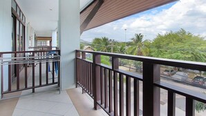 A balcony with a metal railing, a tiled floor, and a view of a street with cars and greenery. - Laem Din Hotel Chaweng (Koh Samui)