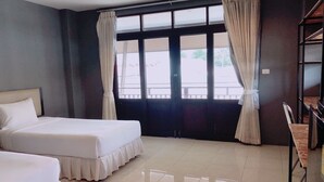 A hotel room with two beds, a desk, and a view of the outdoors through large windows. - Laem Din Hotel Chaweng (Koh Samui)