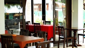 A restaurant with multiple tables and chairs, large windows, and a view of the outside. - Laem Din Hotel Chaweng (Koh Samui)