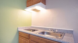 A kitchen with a double sink, wooden cabinets, and a built-in range hood. - Executive Inn and Kitchenette Suites (Eagle Pass)