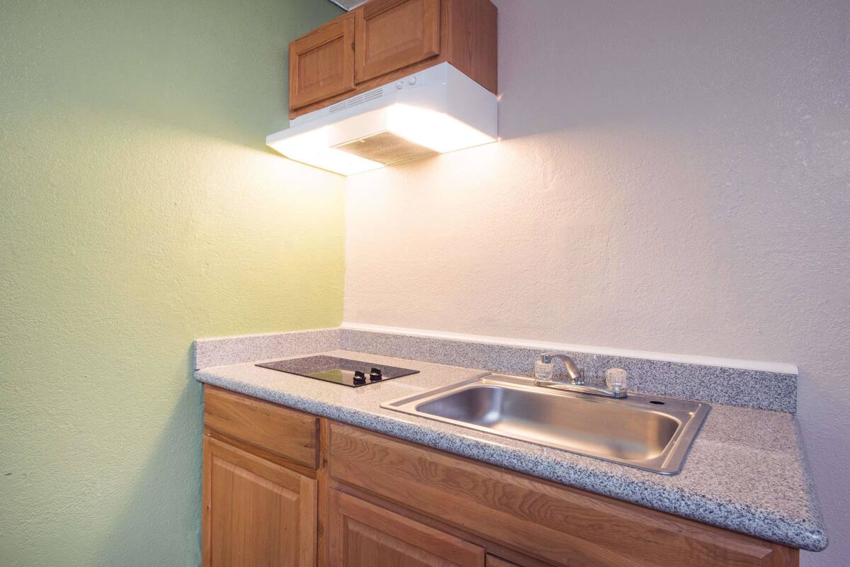 A kitchen with a double sink, wooden cabinets, and a built-in range hood.