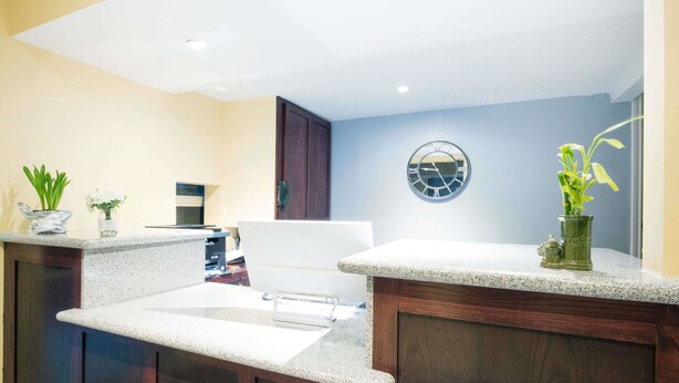 A modern kitchen with granite countertops, wooden cabinets, and a clock on the wall. - Executive Inn and Kitchenette Suites (Eagle Pass)
