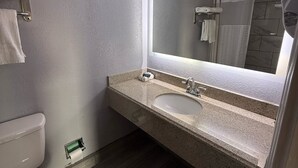 A bathroom with a toilet, sink, and mirror. - Executive Inn and Kitchenette Suites (Eagle Pass)