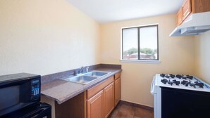 A compact kitchen with a microwave, double sink, and stove.