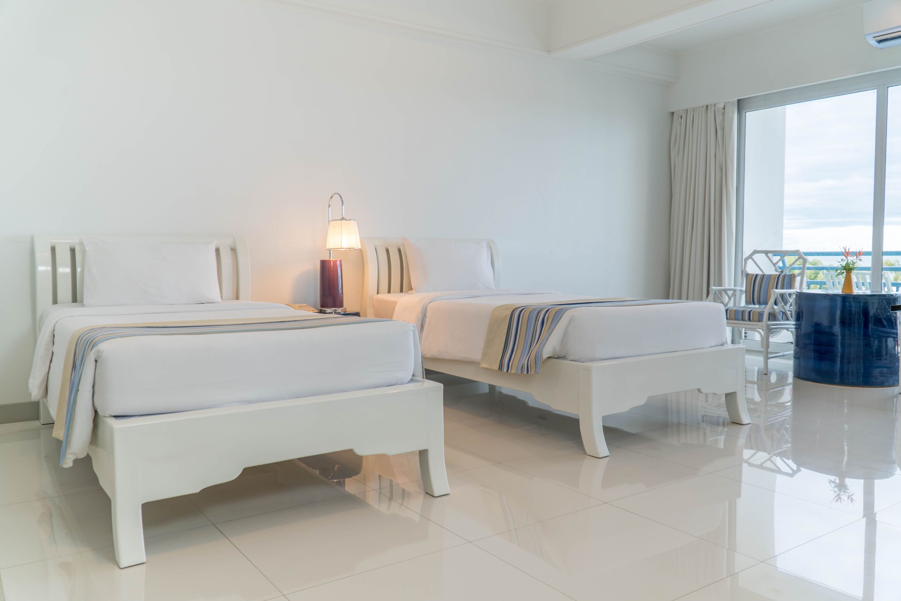 Habitación de hotel con dos camas, un balcón y vistas amplias, y un ventanal grande.