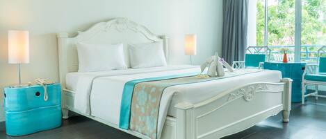 A neatly made bed with a white headboard, two bedside lamps, and a blue suitcase on the floor.
