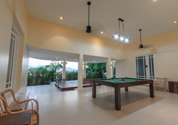 A spacious indoor area with a pool table, seating, and a view of greenery outside. - IndoChine Resort & Villas (Patong)