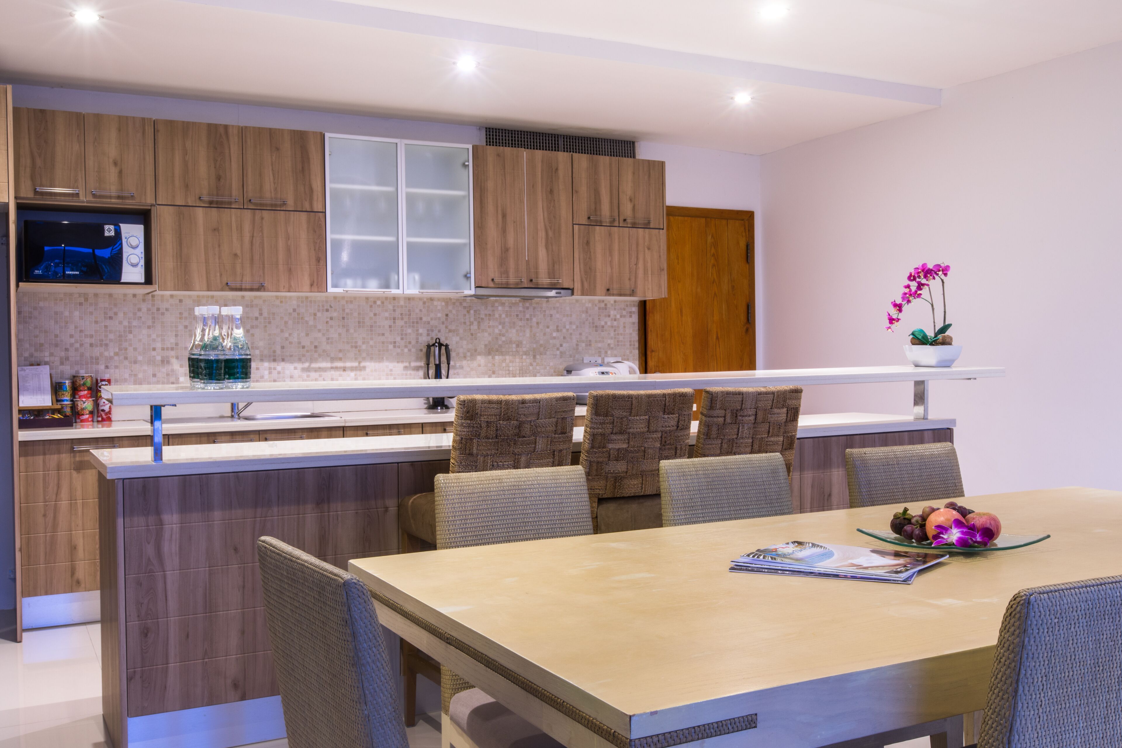 Una cocina moderna con armarios de madera, horno empotrado y un comedor con mesa y sillas.