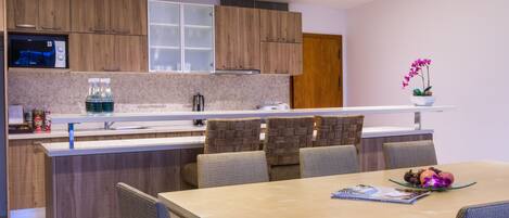 Una cocina moderna con armarios de madera, horno empotrado y un comedor con mesa y sillas.