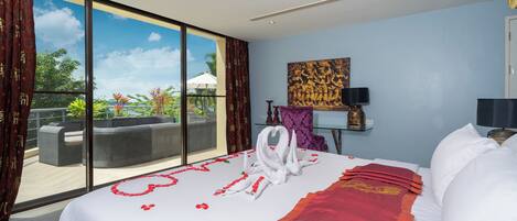 A hotel room with a large bed, a view of the outdoors, a sofa, and a painting on the wall.