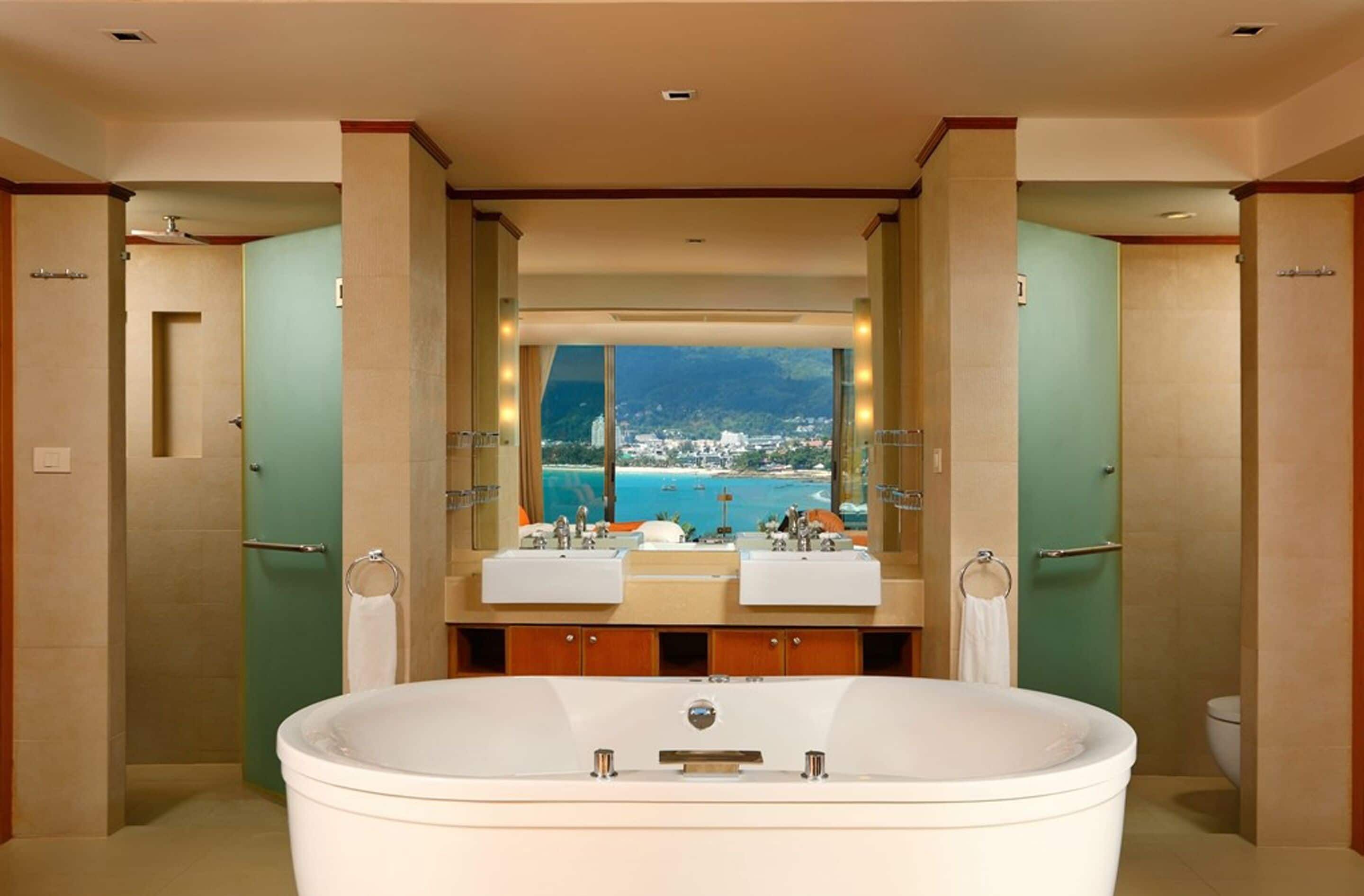 A bathroom with a large bathtub, two sinks, and a view of a coastal city.