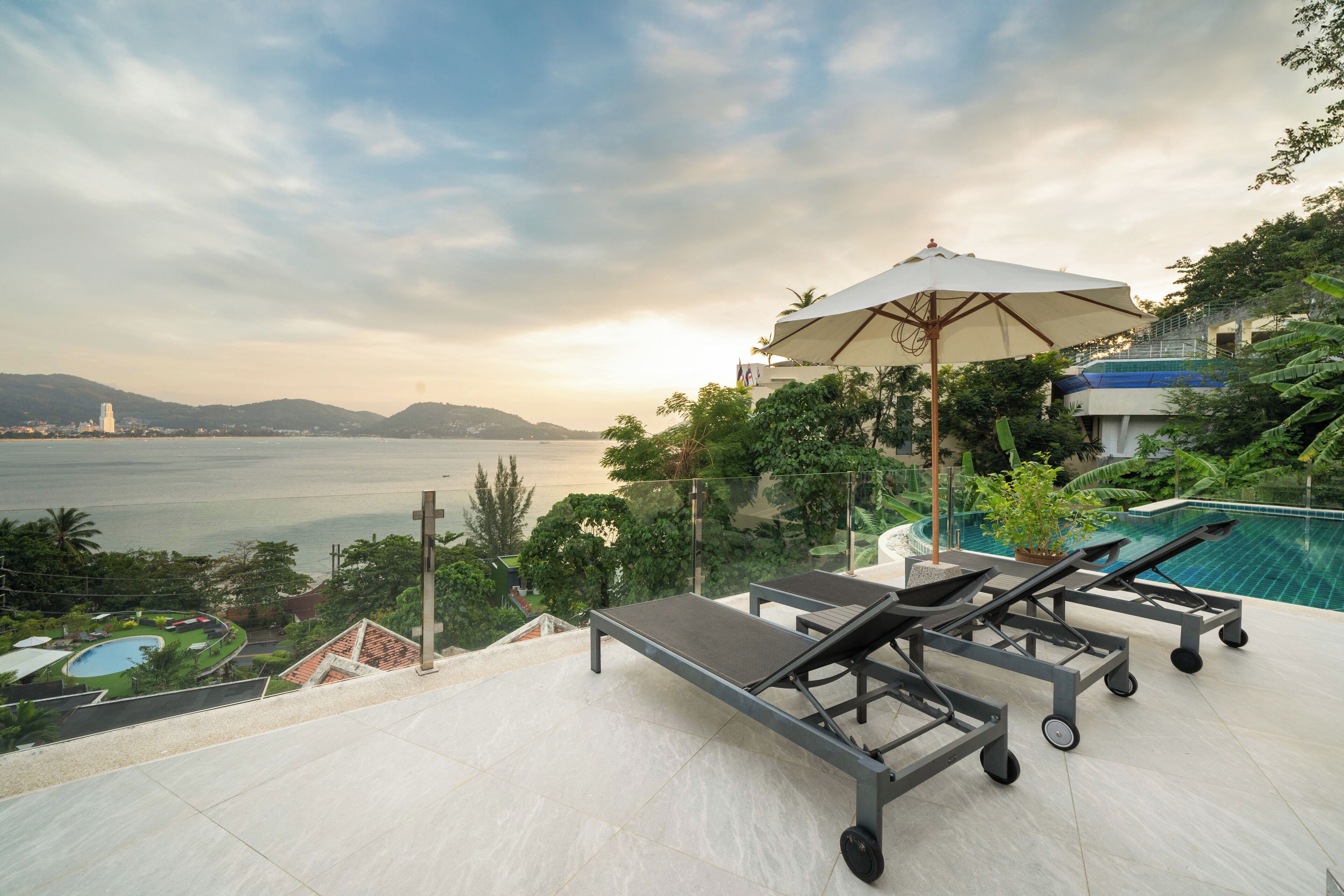 A rooftop terrace with a pool, lounge chairs, and a large umbrella.