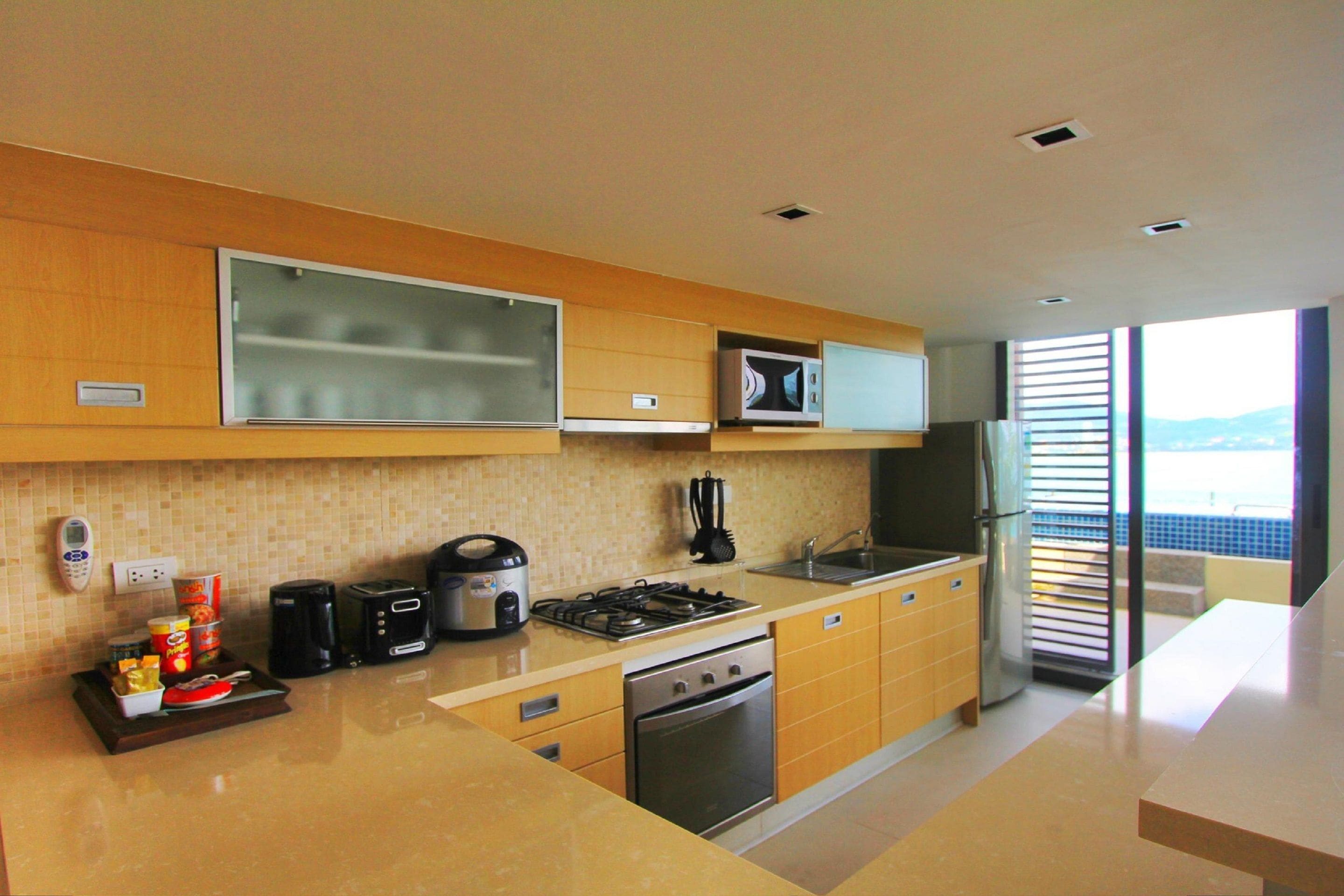 A modern kitchen with a gas stove, oven, microwave, and a large window offering a view.
