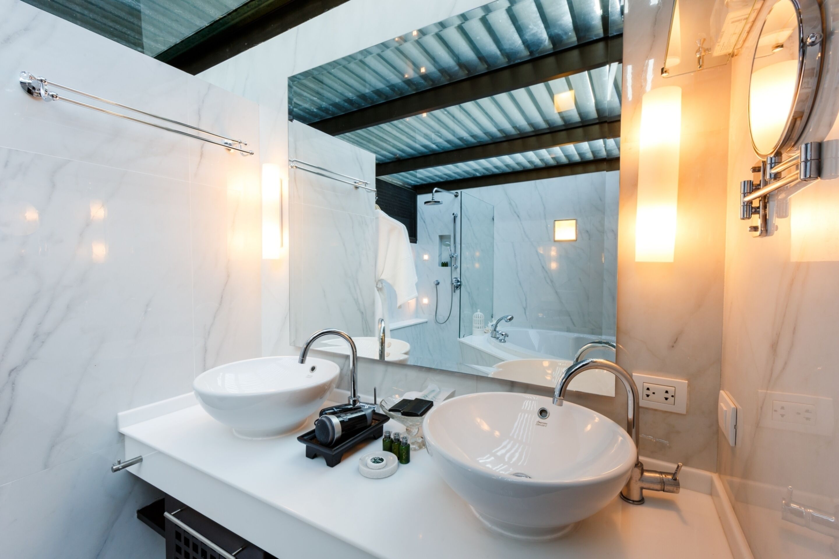 Un baño moderno con dos lavamanos grandes de color blanco, un espejo y una zona de ducha.