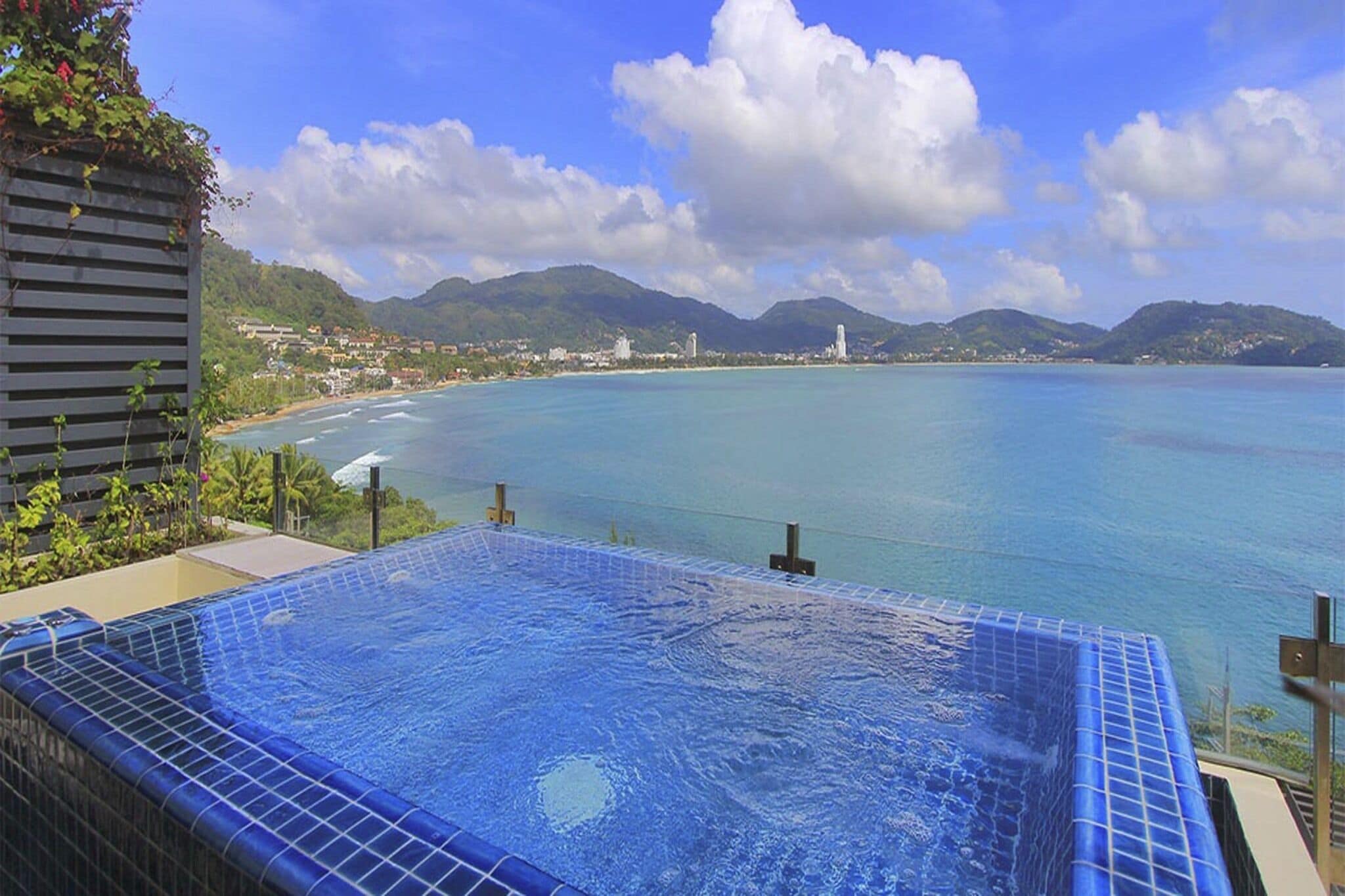 A rooftop infinity pool with a clear view of the coastline and mountains.