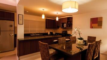 A modern kitchen with dark wood cabinets, a central island with seating, pendant lighting, and a dining table with chairs.