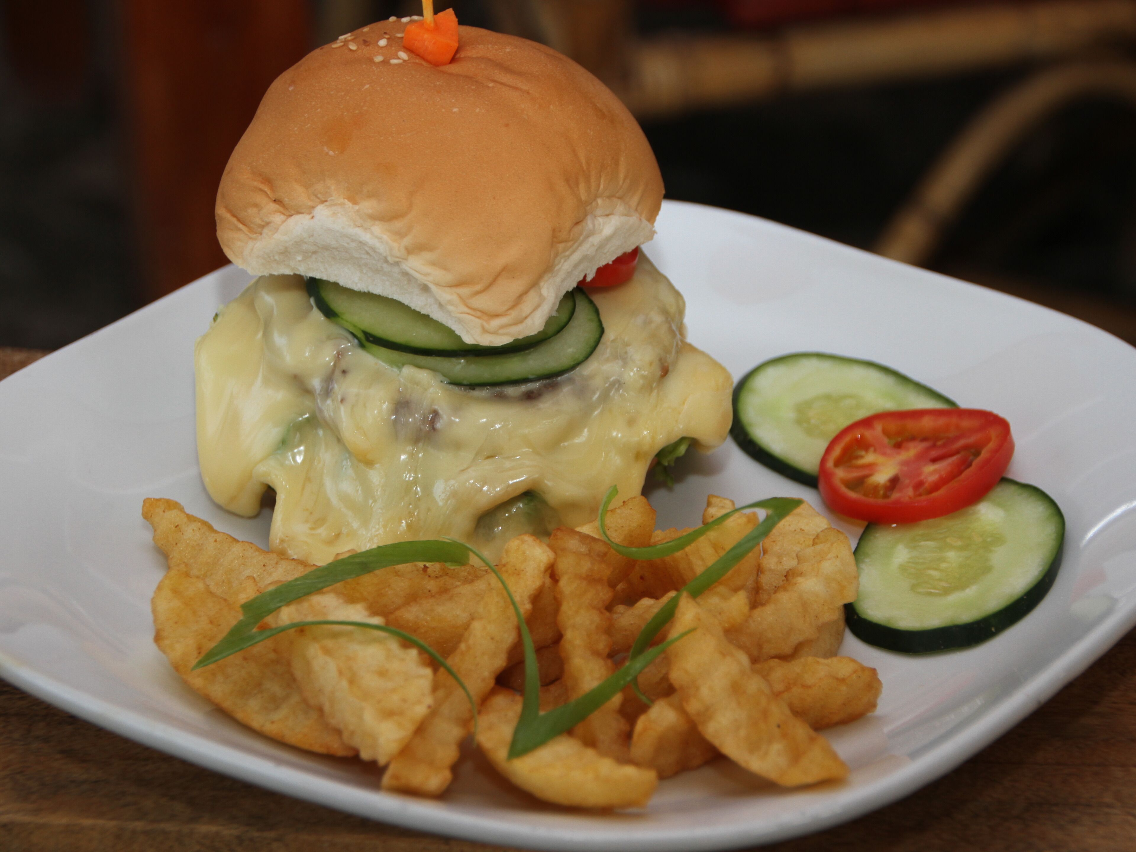 Un plato con una hamburguesa, papas fritas y verduras en rodajas.