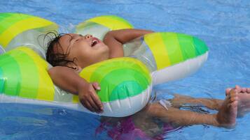 A child in a pool using a green and white inflatable float.