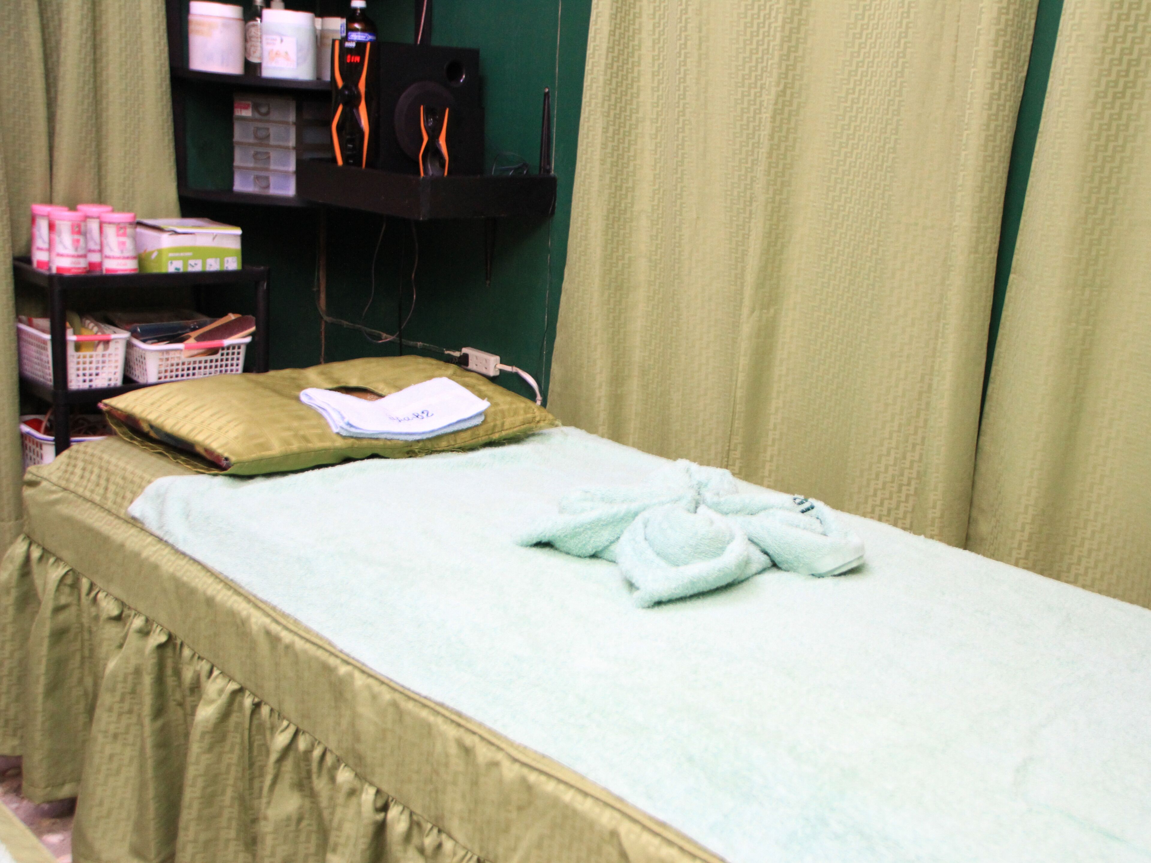 A room with a bed, a shelf with various items, and a curtain.