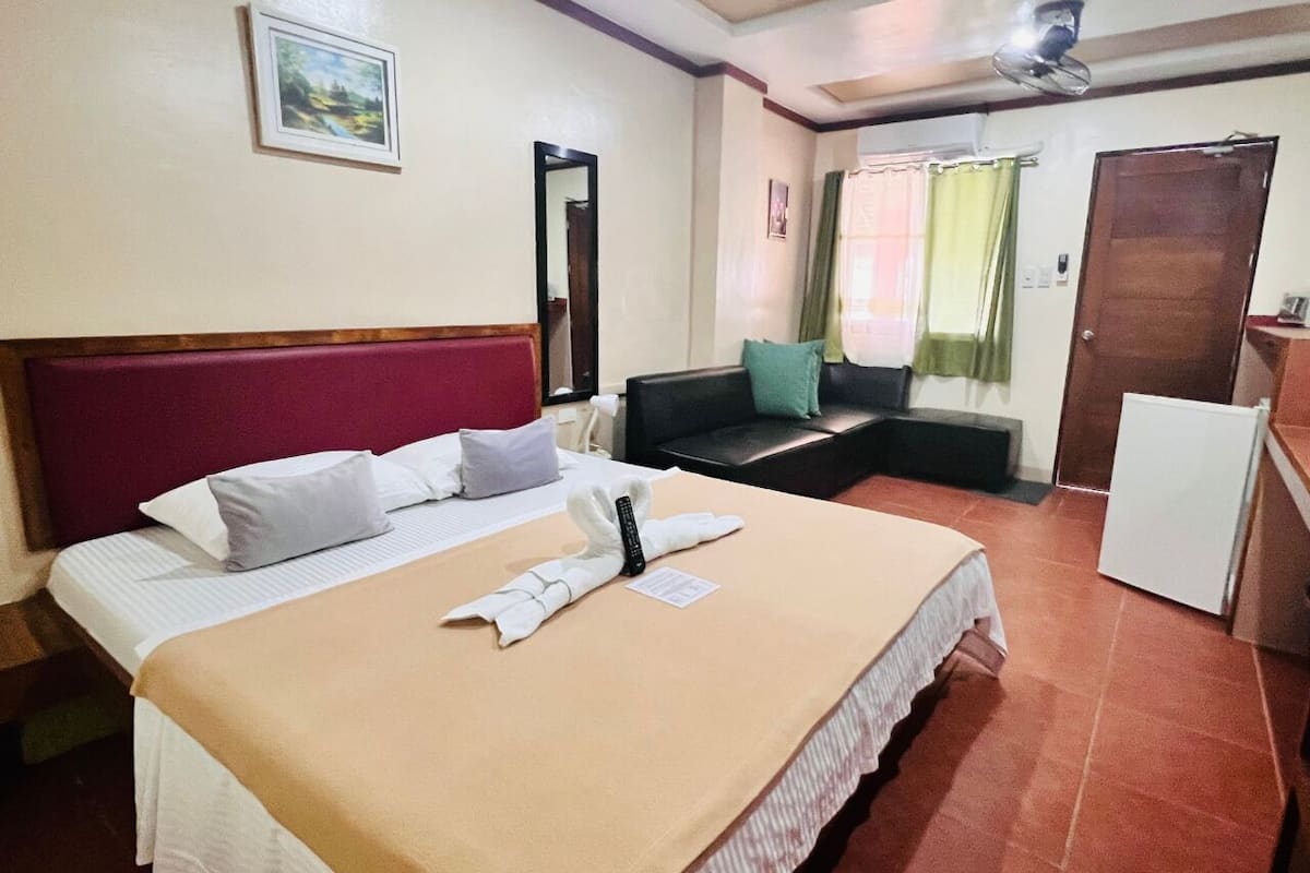 Une chambre d’hôtel avec un lit, un bureau, une chaise, un miroir et une porte.