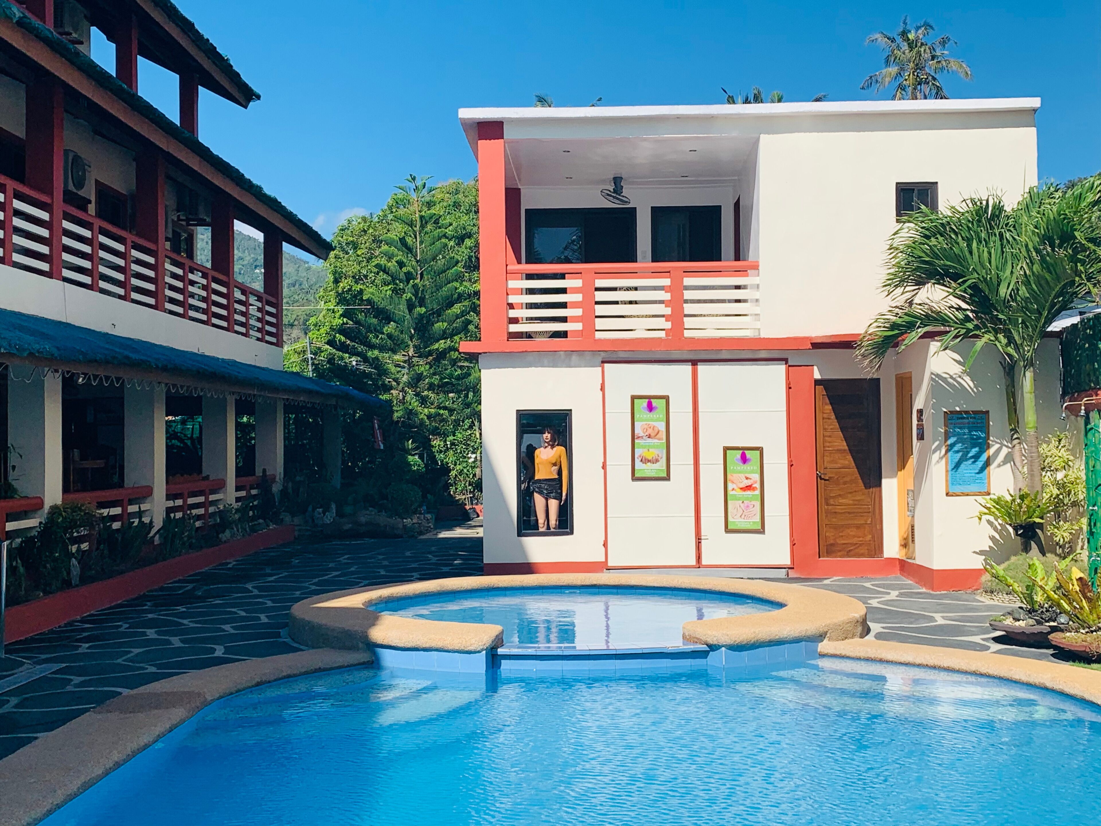 A modern building with a pool, featuring a two-story structure with balconies and a covered outdoor seating area.