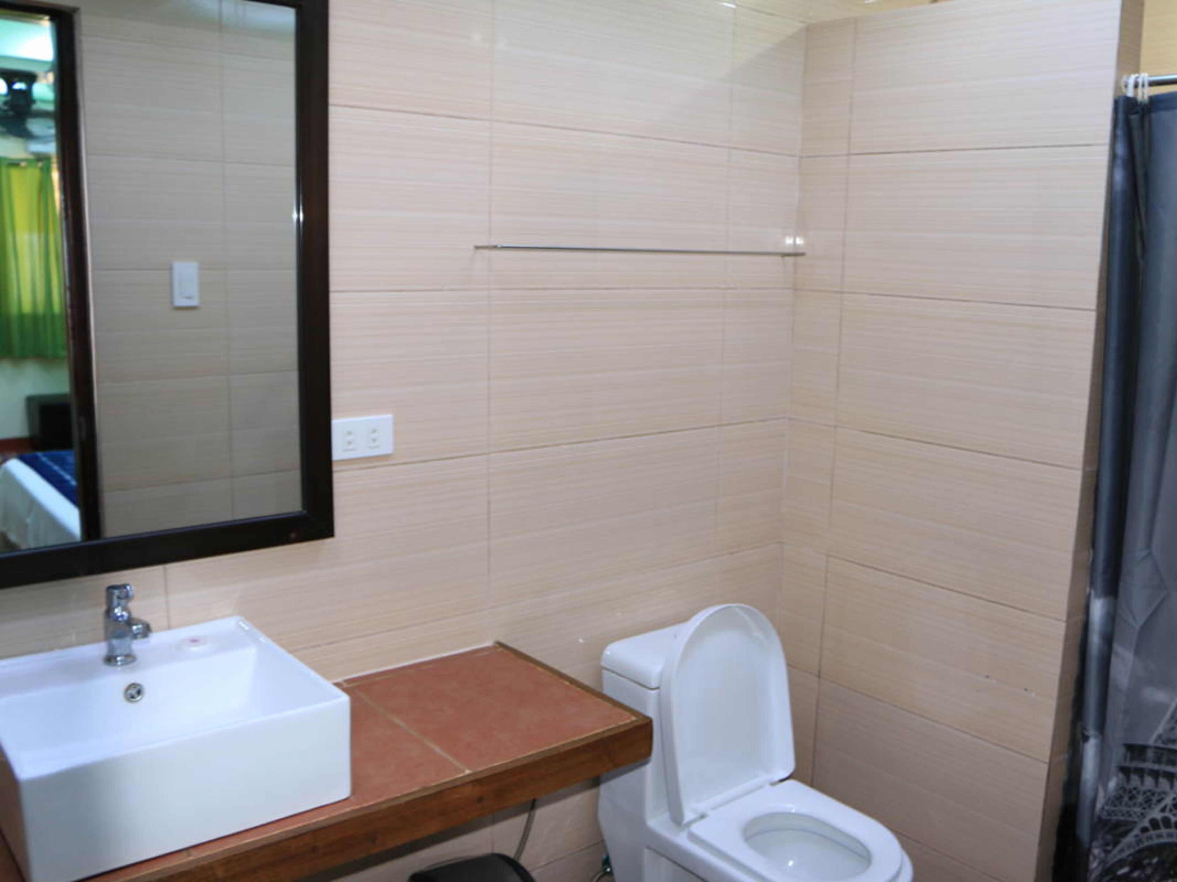 Un baño con lavamanos blanco, inodoro y espejo.