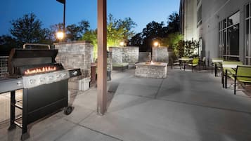 An outdoor patio area with a grill, seating, and a stone wall.