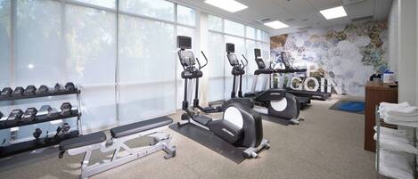 A gym with treadmills, elliptical machines, and dumbbells.