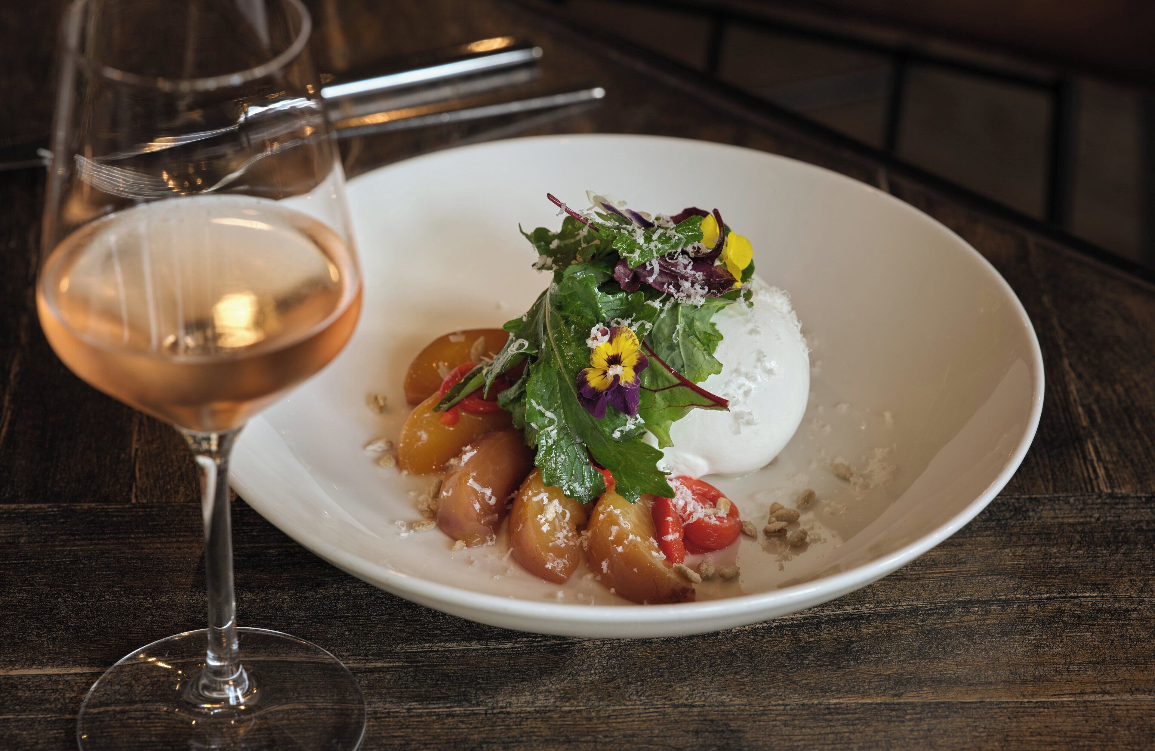 A white plate with a dessert, a glass of wine, and a fork on a wooden table.