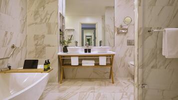 A modern bathroom with a freestanding bathtub, a vanity with two sinks, and a shower area.