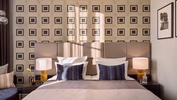 A hotel room with a large bed, two bedside tables with lamps, a patterned wallpaper, and a framed picture on the wall.