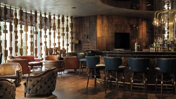 Eine Bar mit Ledersesseln, einer Bar und einer Holzwand mit hängenden Lampen.