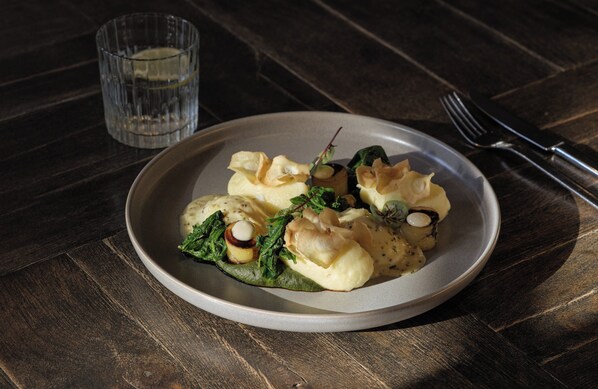 A plate of food on a wooden table with a glass of water and cutlery. - The Posthouse Berlin Potsdamer Platz - Leonardo Limited Edition (Berlin)