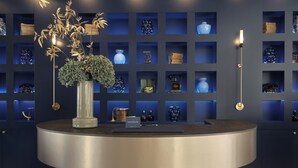 Un mostrador de recepción circular con un letrero que dice "POSTHOUSE" en un interior moderno con estanterías azules que exhiben varios artículos.