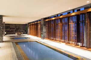 Un área de piscina interior moderna con varias piscinas y paneles de madera para mayor privacidad.