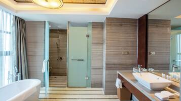 A modern bathroom with a large bathtub, a walk-in shower, and a vanity with a large mirror.