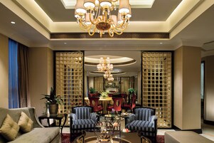 Un vestíbulo amplio con candelabro, zona de estar y paneles decorativos.