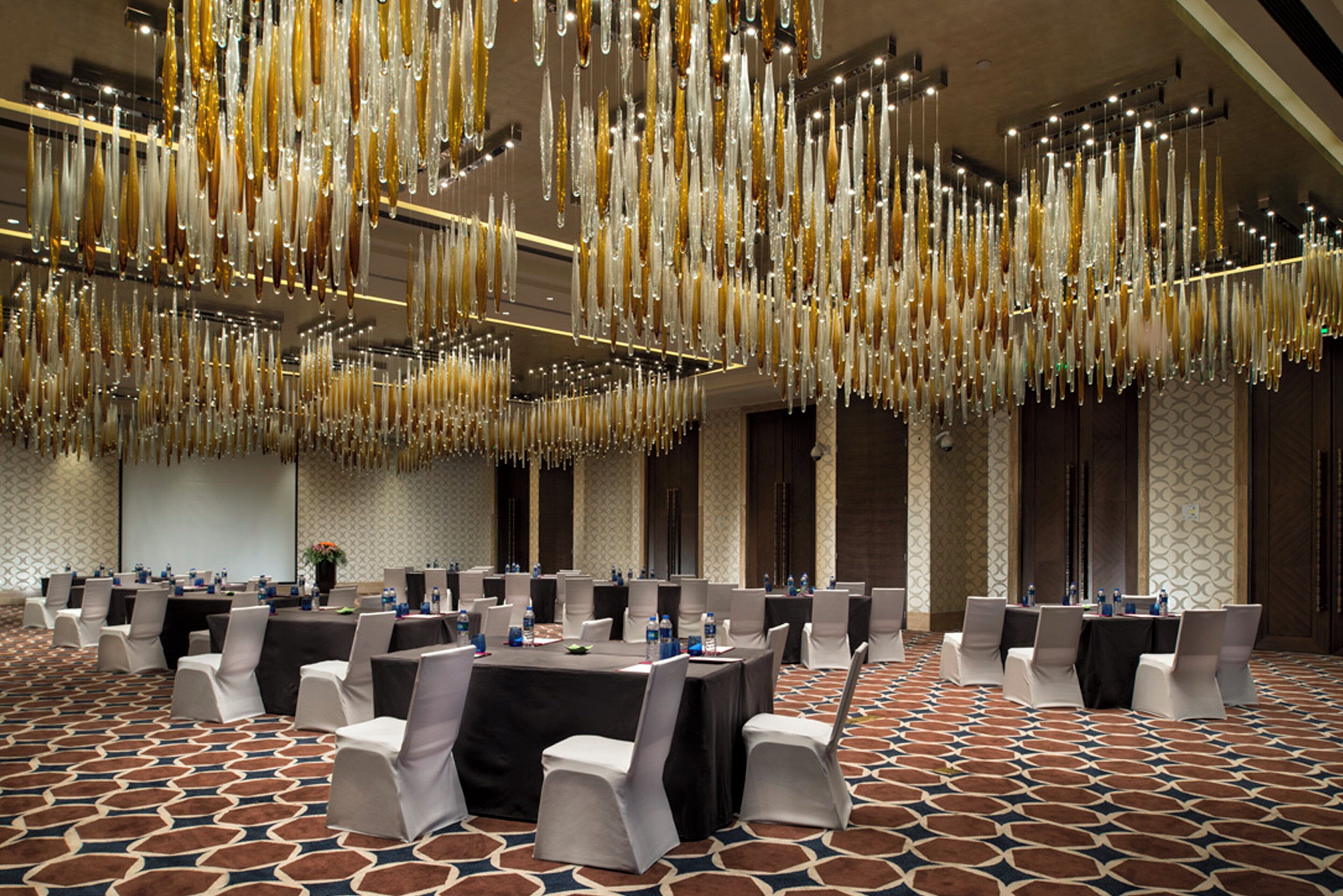 A conference room with tables and chairs, a patterned carpet, and hanging decorations.