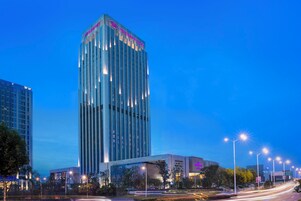 Un hotel de gran altura con un diseño moderno, que destaca por su señalización prominente en la parte superior.