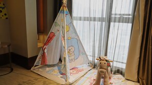 A child's play tent with cartoon characters, a plush toy, and a patterned mat on the floor.