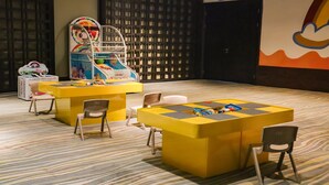 A play area with a yellow play table, chairs, and a carousel.