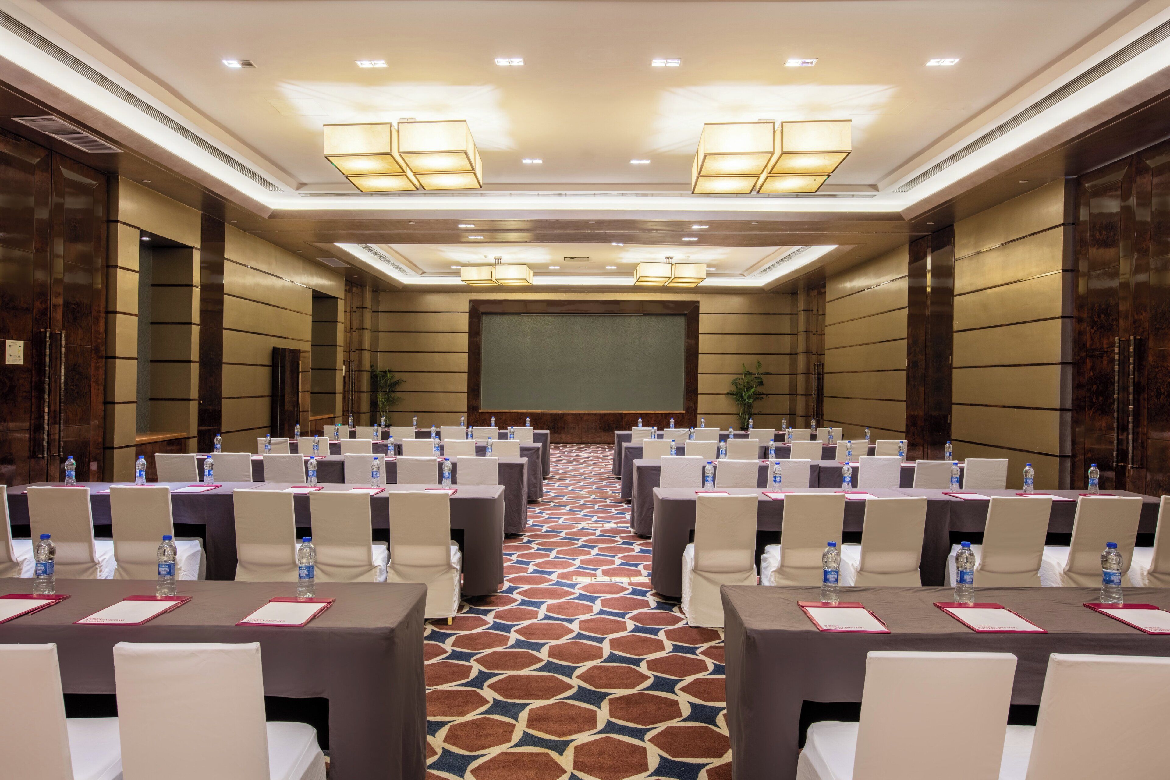 A conference room with rows of tables and chairs, equipped with water bottles and nameplates.