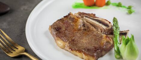 Un plato con un bistec, espárragos y zanahorias.